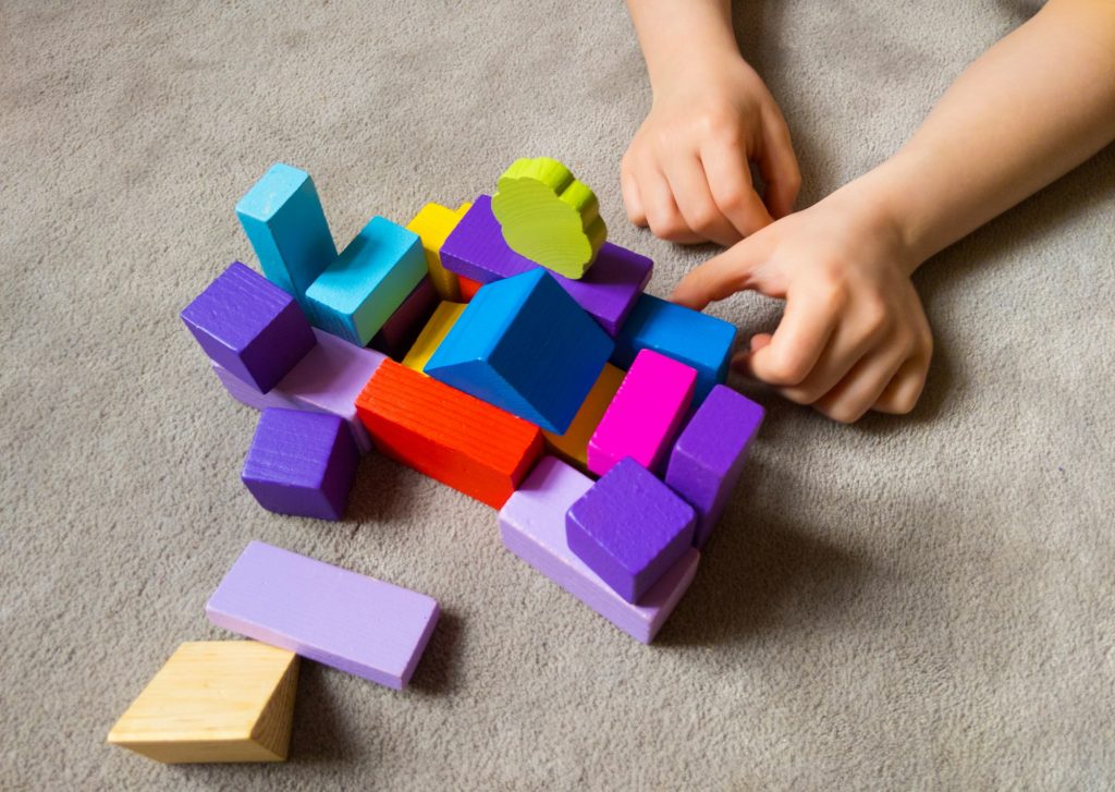 A child is playing withcolorful heart with colorful wooden building blocks.